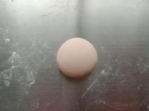 21.取20克粉色面团揉圆，稍微压扁一点
