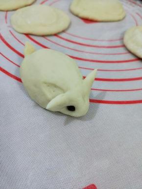 然后用拇指和食指在耳朵下面一点的地方，轻轻压下去，再沾上红豆做眼睛。