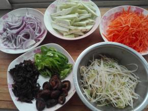 将洋葱切丝、茄子去皮切成约手指宽的细条、胡萝卜切丝、青椒切丝