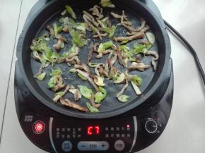 开始最后的一轮操作，将前面处理好的肉丝葱蒜，均匀的铺在电饼铛底盘上。