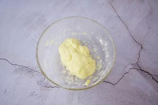 把称好的奶粉放入容器中，边加入牛奶边用刮刀拌，然后用手抓成团，奶粉团不要太软，硬一些为好