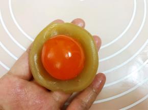 莲蓉馅压扁包入一个咸蛋黄