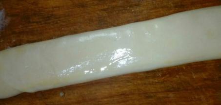 将面团长条按压成扁长状，厚度约为0.6cm,用刷子刷上鸡蛋液