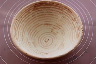 在发酵藤篮中倒入面粉，转动藤篮，让面粉均匀的附着在藤篮上。
