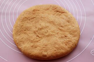 把松驰好的面团再次排气后，用手摁成厚一点的面团。