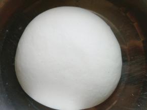 边用手搅动面粉边倒热水（注意不是开水，面团中可加一点盐），把面粉活成柔软的面团，面团表面用刷子刷一点植物油，盖保鲜膜醒发最少一小时。