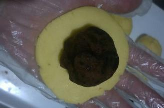 取一个面团，按扁圆，周边薄中间厚一点，放入豆沙馅