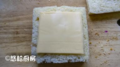 盖上一片吐司，上面放芝士片，再盖上一片吐司，从对角线切开也行，从中间切开也行，根据自己的喜好来哦。