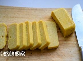 放凉后的年糕倒扣在案板上，切片。放凉的黄面糕很硬，不好吃。
