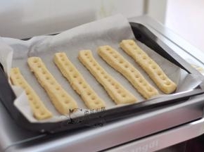 取出烤盘，在每个面条上用筷子按压小孔，表面再刷一层蛋液。