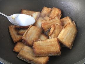 放入煎好的带鱼并把2勺的白糖均匀的撒在鱼上面。