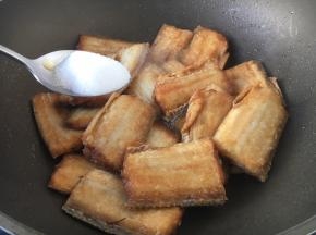 放入煎好的带鱼并把2勺的白糖均匀的撒在鱼上面。