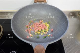 起锅，加一点点油烧热，下入玉米粒、豌豆粒、火腿丁