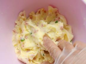 戴上手套，把蒸熟的土豆压成泥，再加入火腿肠碎、葱花、沙拉酱、盐拌匀分成16份，每份18克备用。