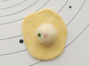 取一份小面团擀开，放入一枚土豆泥馅包好，收口收紧朝下。