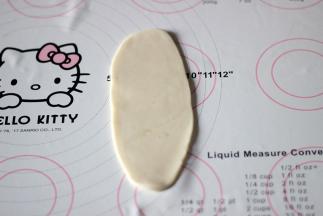 将包好的面团放在工作台上，擀成牛舌状