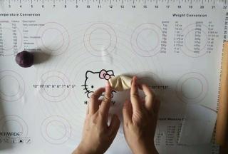 取出面团，用手指从中间按一下，两边的面团往中间挤压后再次按扁