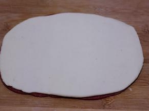 把白色的面皮铺在红色面皮的上面。
