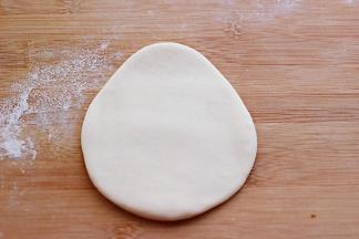 
现在开始做圣诞老人的头部、取一块白色面团揉匀擀成上窄下宽的椭圆形面团。

