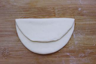 另取一块面团揉匀、擀成椭圆形后对折一下、不要对折的太齐、如图