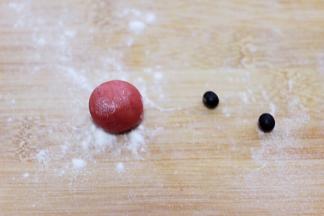 取一小点红色面团做一个小圆蛋做圣诞老人的鼻子、准备好两颗黑豆