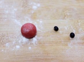 取一小点红色面团做一个小圆蛋做圣诞老人的鼻子、准备好两颗黑豆