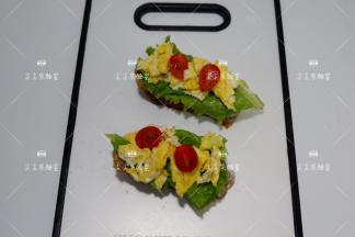 在放上炒好的鸡蛋和小番茄