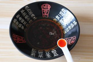 熬煮好的酸汤倒入面碗内，加入一小勺红油；