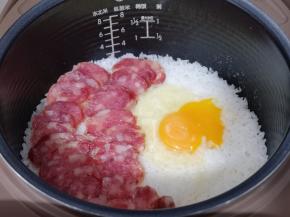 再把切好的腊肠摆放在米饭上面，将鸡蛋磕米饭上！盖上盖子继续煮饭模式5分钟，这时电饭煲掉到保温，不要急着打开盖子，焖15分钟！