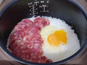再把切好的腊肠摆放在米饭上面，将鸡蛋磕米饭上！盖上盖子继续煮饭模式5分钟，这时电饭煲掉到保温，不要急着打开盖子，焖15分钟！