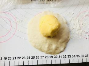 将面团按扁，排掉边缘的气泡。将馅料置于中间位置