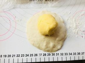 将面团按扁，排掉边缘的气泡。将馅料置于中间位置