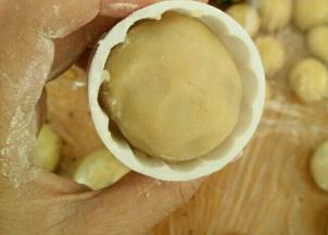 放点熟粉到月饼模具里，转一圈再倒出来。把月饼坯放进去，用力往下压出月饼。同时烤箱上下管预热190度。