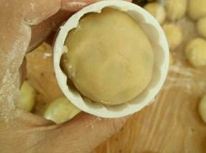 放点熟粉到月饼模具里，转一圈再倒出来。把月饼坯放进去，用力往下压出月饼。同时烤箱上下管预热190度。