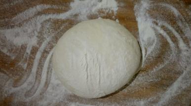 面板撒适量干面粉，将面团揉搓排出气泡，尽量多揉一会。揉圆按扁