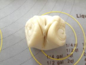 松弛好的酥皮轻轻的在中间压痕用手两端向中间捏合压扁