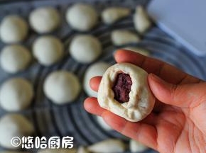 分开的小面团揉光滑，擀开，包入14克左右的豆沙馅，像包包子一样捏紧收口。