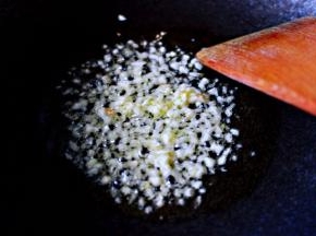 另起锅倒入花生油烧热后、放入用刀切碎的蒜末爆出香味后。