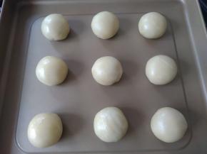 做好后放在不粘烤盘上，表面刷上蛋黄液，沾上白芝麻