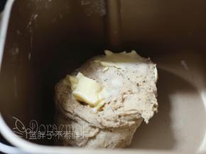 10分钟后，面包机休息时，这时候面团可以拉出厚厚的膜，加入软化好的黄油。