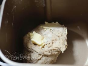 10分钟后，面包机休息时，这时候面团可以拉出厚厚的膜，加入软化好的黄油。