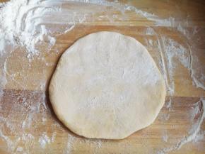 用擀面杖将面团擀平，并在上边再撒上面粉。

