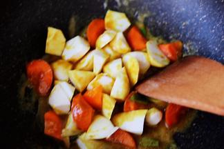 这个时候放入切块的芋头和胡萝卜，继续用锅铲翻炒片刻。