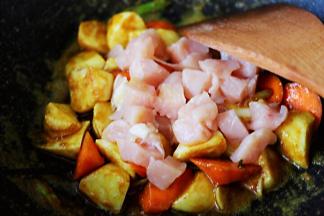 看见芋头和胡萝卜炒至变软时，放入切块的鸡脯肉。