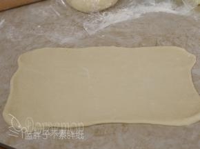 将松弛好的面团用擀面杖擀成长方形。