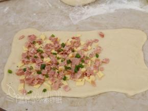 面团的2/3处放上培根、芝士和香葱，最后撒上黑胡椒粉，芝士粉。