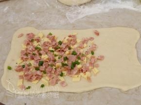 面团的2/3处放上培根、芝士和香葱，最后撒上黑胡椒粉，芝士粉。