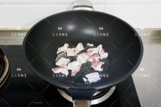 起锅热油，加入五花肉煎炒至微焦出油