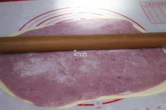 第一层放白色面皮，第二层放紫薯面皮，并用擀面杖再次压紧实，卷起。