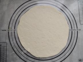 取其中一个面团擀成比披萨盘略大一些的圆形。